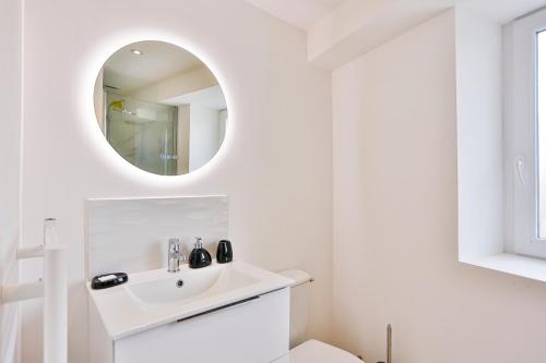a white bathroom with a sink and a mirror at Little Factory - T2 avec parking in Vierzon