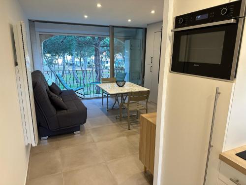 ein Wohnzimmer mit einem TV und einem Tisch mit Stühlen in der Unterkunft CYEL CATALAN in Argelès-sur-Mer