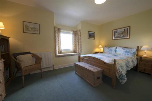 a bedroom with a bed and a chair and a window at Bank Top Cottage Coniston in Coniston