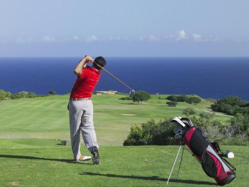 un homme balançant un club de golf sur un parcours de golf dans l'établissement Erika27 B&B NO LOADSHEDDING, à Dana Bay