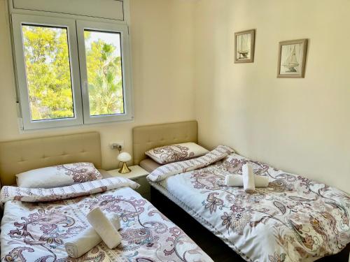 two twin beds in a room with two windows at Apartment in Salou next to the beach for families,WIFI in Salou