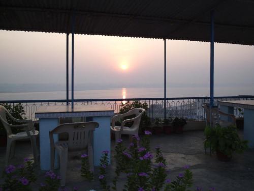 a table and chairs on a balcony with the sunset at Hotel Temple On Ganges in Varanasi