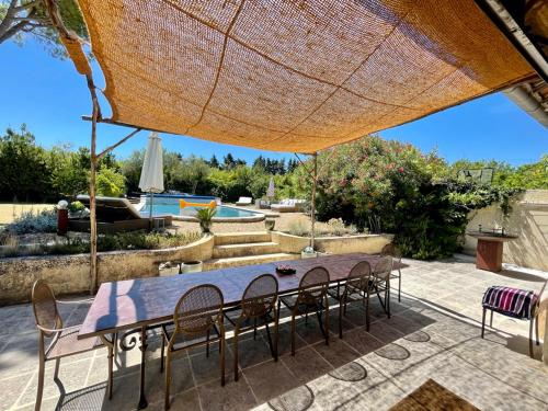 a table and chairs under a large umbrella at Le Mas des Perrines Maison d’Hôtes in Pernes-les-Fontaines