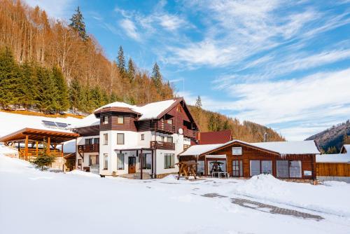 a large house in the snow in the mountains at Pensiunea Popas in Apuseni in Răchiţele