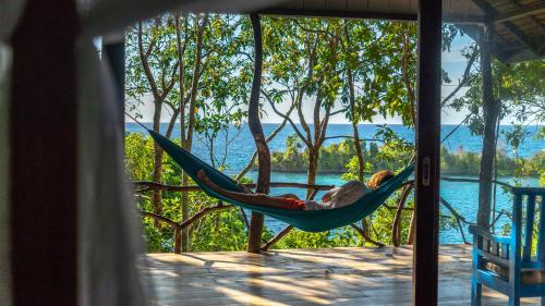 a man sleeping in a hammock on a porch at Araya Dive Resort Togean in Bomba