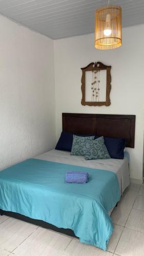 a bedroom with a bed with blue sheets and a chandelier at Pousada Suítes Sete Mares in Guarujá