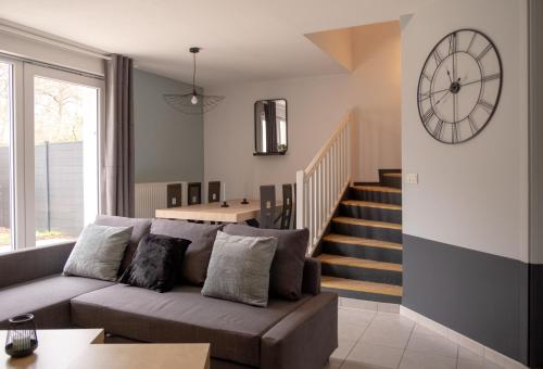 a living room with a couch and a clock on the wall at Maison - Le Terra Verde - Terrasse in Haguenau