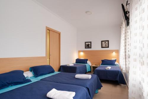 a room with two beds with blue sheets at Hostal Mitre Paterna in Paterna