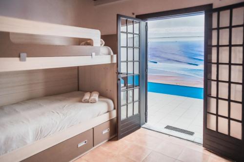 a room with bunk beds and a door leading to the ocean at Estúdios Lagido - Peniche Surf Camp Working Space & surf in Ferrel