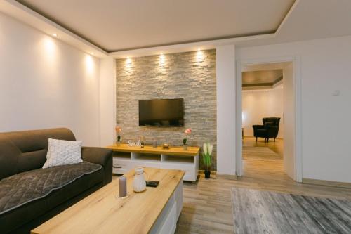 - un salon avec un canapé et une télévision sur un mur en briques dans l'établissement Backa idila, à Bački Gračac