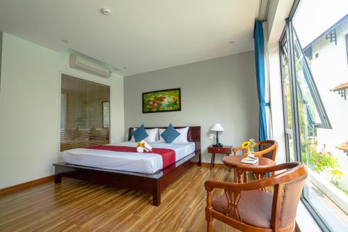 a bedroom with a bed and a table and a chair at Golden Star Villa Hoi An in Hoi An
