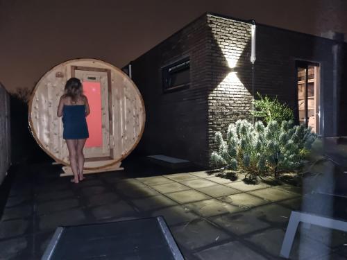 a woman in a blue dress standing in front of a door at Luxe wellness woning met prive buitensauna in Ermelo