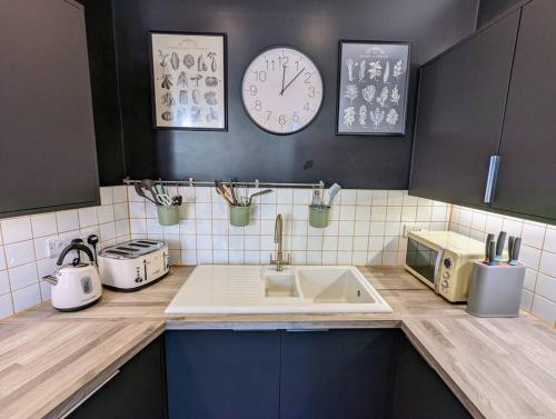 a kitchen with a sink and a clock on the wall at Ramsgate Retreat - ultra modern 3 bed in Ramsgate