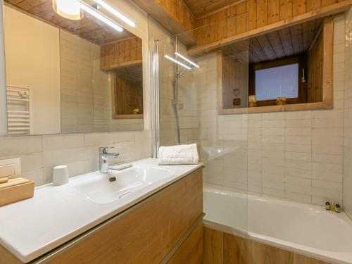 une salle de bain avec un lavabo, une baignoire et un miroir dans l'établissement Élégant appartement rénové avec wifi au cœur du vieux Val-d'Isère, proche des pistes et commodités - FR-1-694-313, à Val dʼIsère