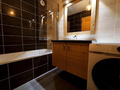 La salle de bains est pourvue d'un lavabo, d'une baignoire et d'un lave-linge. dans l'établissement Appartement lumineux 2 chambres, terrasse sud, parking, WiFi - FR-1-624-128, à Samoëns