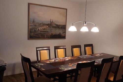 a dining room table with chairs and a painting on the wall at Erbgericht Putzkau in Putzkau