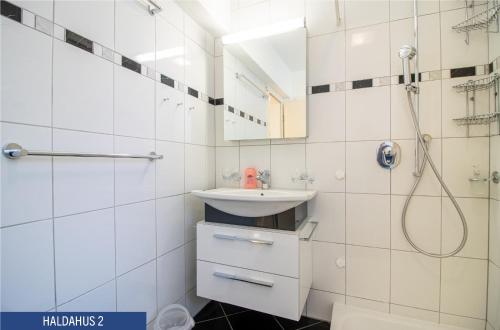 a white bathroom with a sink and a shower at Haus Haldahus by Arosa Holiday in Arosa