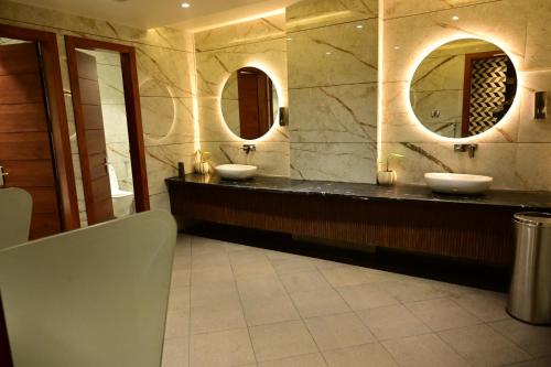 a bathroom with two sinks and two mirrors at THE PARKQUEEN in Rohtak