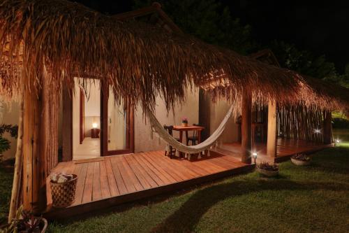 a wooden deck with a hammock and a hut at Pousada Tatuá in Pôrto de Pedras