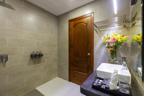 Blanc Smith Hotel في سيام ريب: حمام مع حوض و مزهرية من الزهور