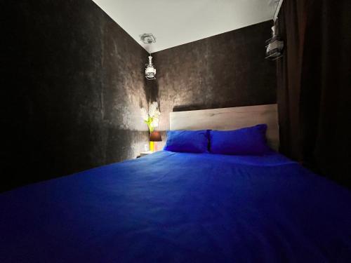 a bedroom with a blue bed with a black wall at Sport Hotel Terra in Ustʼ-Kamenogorsk