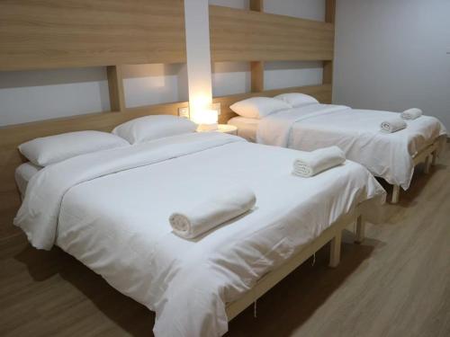 three beds in a room with white sheets and towels at Boon Street Hostel in Bangkok