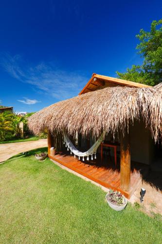 a straw hut with a grass roof on a yard at Pousada Tatuá in Pôrto de Pedras