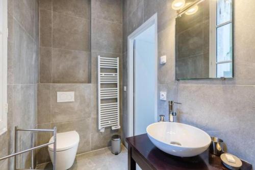 bagno con lavandino, servizi igienici e specchio di Magnifique Appartement avec climatisation en Hyper Centre de Bordeaux a Bordeaux