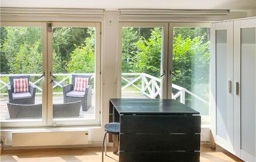 a screened in porch with a black desk and chairs at Amazing Home In Vaxholm With Kitchen in Vaxholm