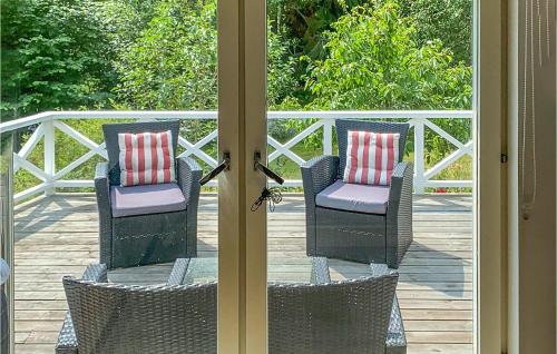 two wicker chairs sitting on a deck with a glass door at Amazing Home In Vaxholm With Kitchen in Vaxholm