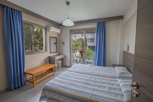 een slaapkamer met een bed, een bureau en ramen bij Ayia Napa Holiday Apartment So1 in Ayia Napa