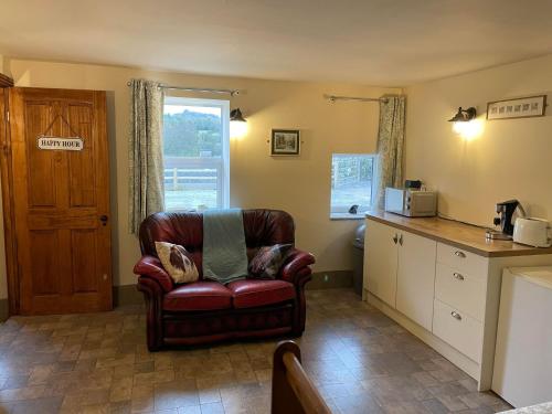 a living room with a leather chair and a kitchen at Boujie Barn- Stable in Waterfall