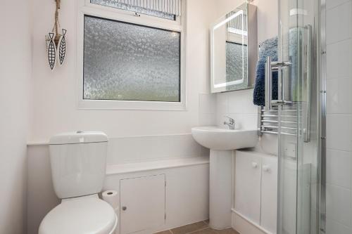 a white bathroom with a toilet and a sink at Chalet Seashell in Dartmouth