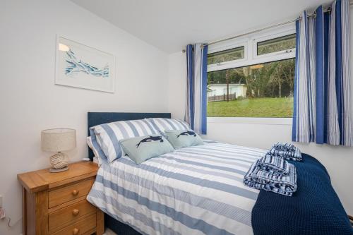 a bedroom with a bed and a window with blue curtains at Chalet Seashell in Dartmouth