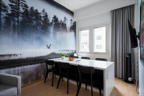 a dining room with a table and chairs with a forest mural at Hiisi Hotel Lohja in Lohja