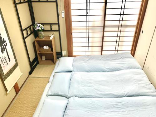 a room with a bed with white sheets at 花楓舎-Sakura & Maple Guest House-ゲストハウス in Kyoto