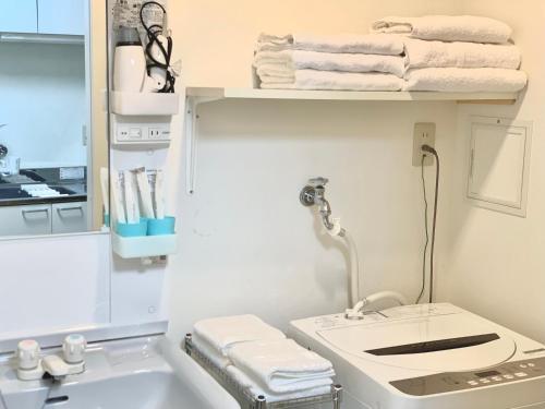a bathroom with a sink and a shelf with towels at 花楓舎-Sakura & Maple Guest House-ゲストハウス in Kyoto