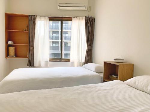 two beds in a room with a window at 花楓舎-Sakura & Maple Guest House-ゲストハウス in Kyoto