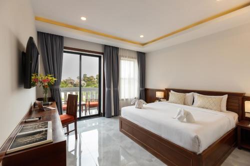 um quarto com uma cama grande e uma varanda em Blanc Smith Hotel em Siem Reap