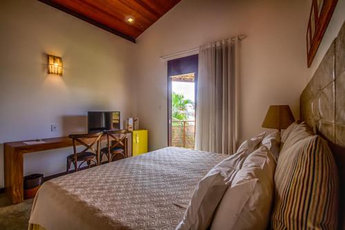 Schlafzimmer mit einem Bett, einem Schreibtisch und einem Fenster in der Unterkunft Aruanã Eco Praia Hotel in Aracaju