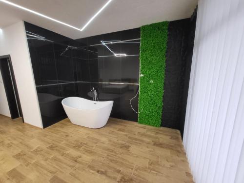 a bathroom with a white tub and a green wall at Вилно селище PARADISE VIEW in Sarnitsa
