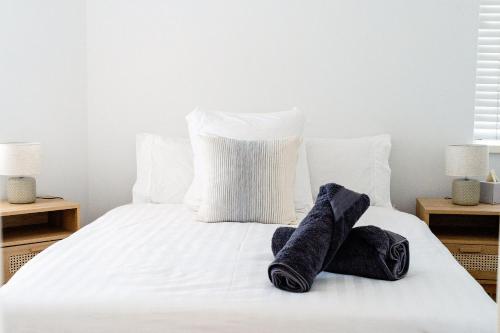 a white bed with two pairs of socks on it at Cottesloe Beach View Apartments #11 in Perth