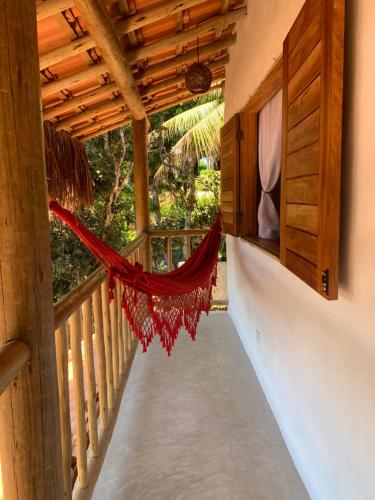 a hammock on the balcony of a house at Casa Jandaia Trancoso - apartamento superior in Trancoso