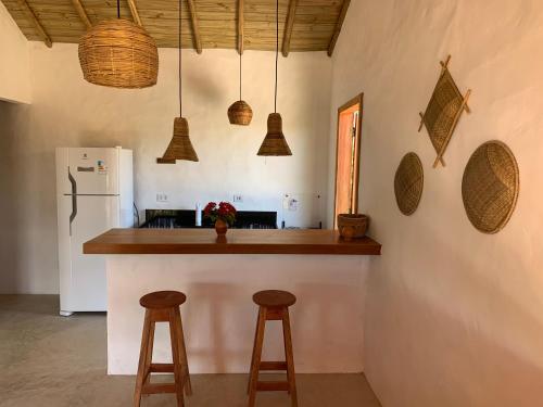 a kitchen with a counter with stools and a refrigerator at Casa Jandaia Trancoso - apartamento superior in Trancoso