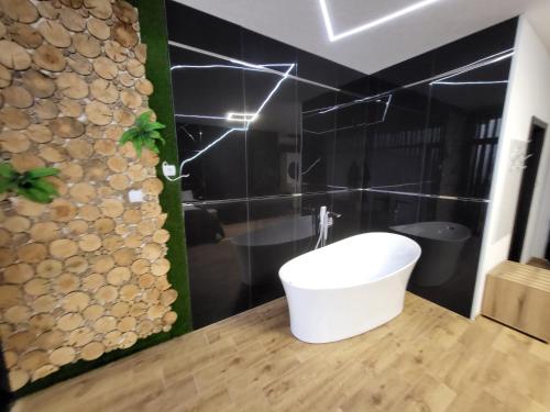 a bathroom with a white bath tub on a wooden floor at Вилно селище PARADISE VIEW in Sarnitsa