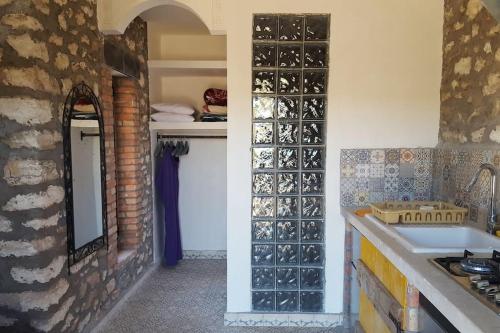 a kitchen with a sink and a wall with wine bottles at studio en pierres traditionnelle in Essaouira