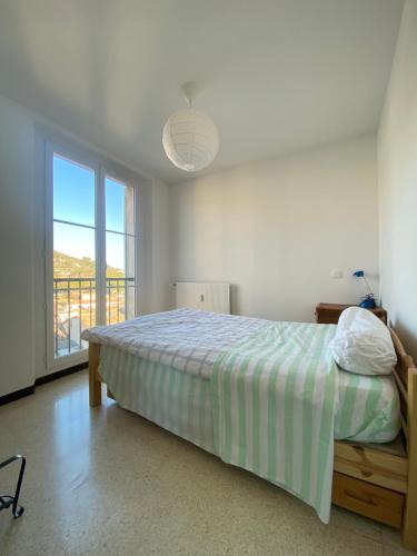 une chambre avec un lit et une grande fenêtre dans l'établissement Appartement deux chambres centre historique avec ascenseur et garage, à Manosque