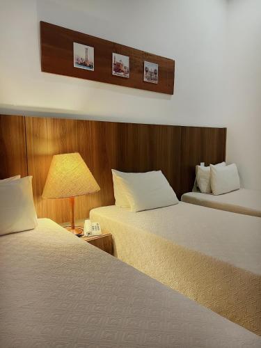a hotel room with two beds and a lamp at Aruanã Eco Praia Hotel in Aracaju
