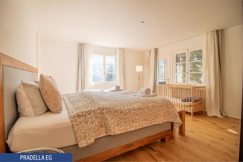 a bedroom with a bed and two windows and a crib at Chalet Pradella by Arosa Holiday in Arosa