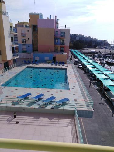 a large swimming pool with blue chairs and umbrellas at Apartemento da Marina in Albufeira